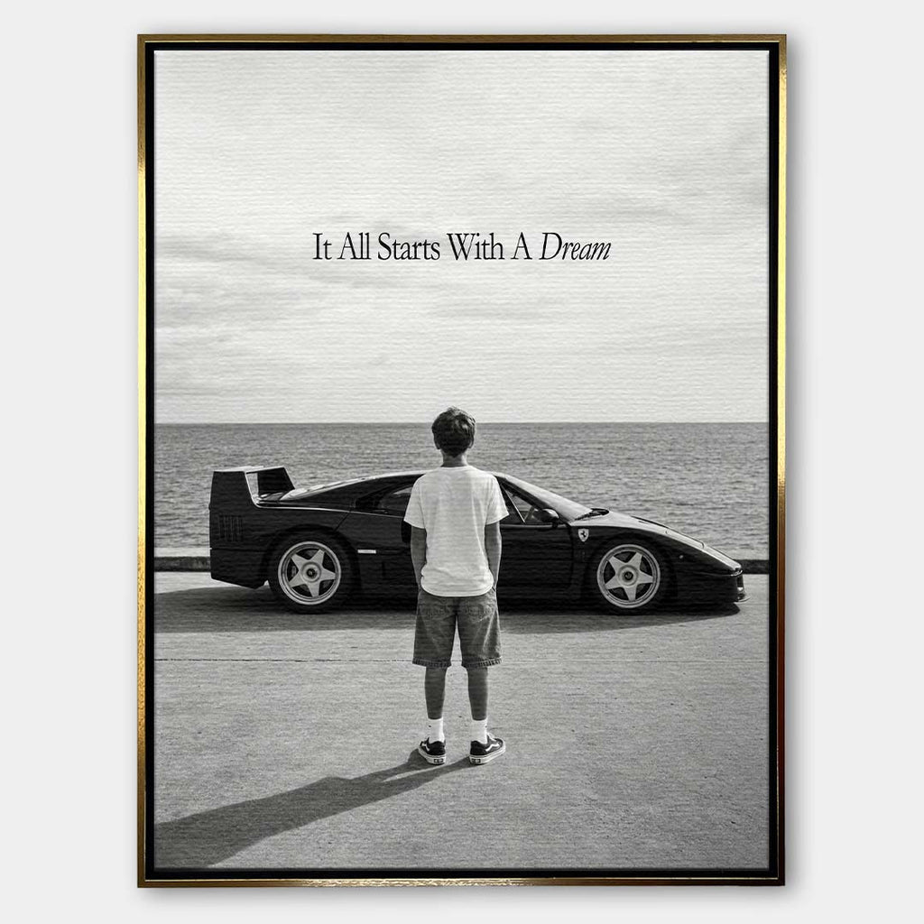 Czarno-biały obraz na płótnie przedstawiający chłopca patrzącego na sportowe auto i morze. Wydruk galeryjny z motywacyjnym napisem It All Starts With A Dream.