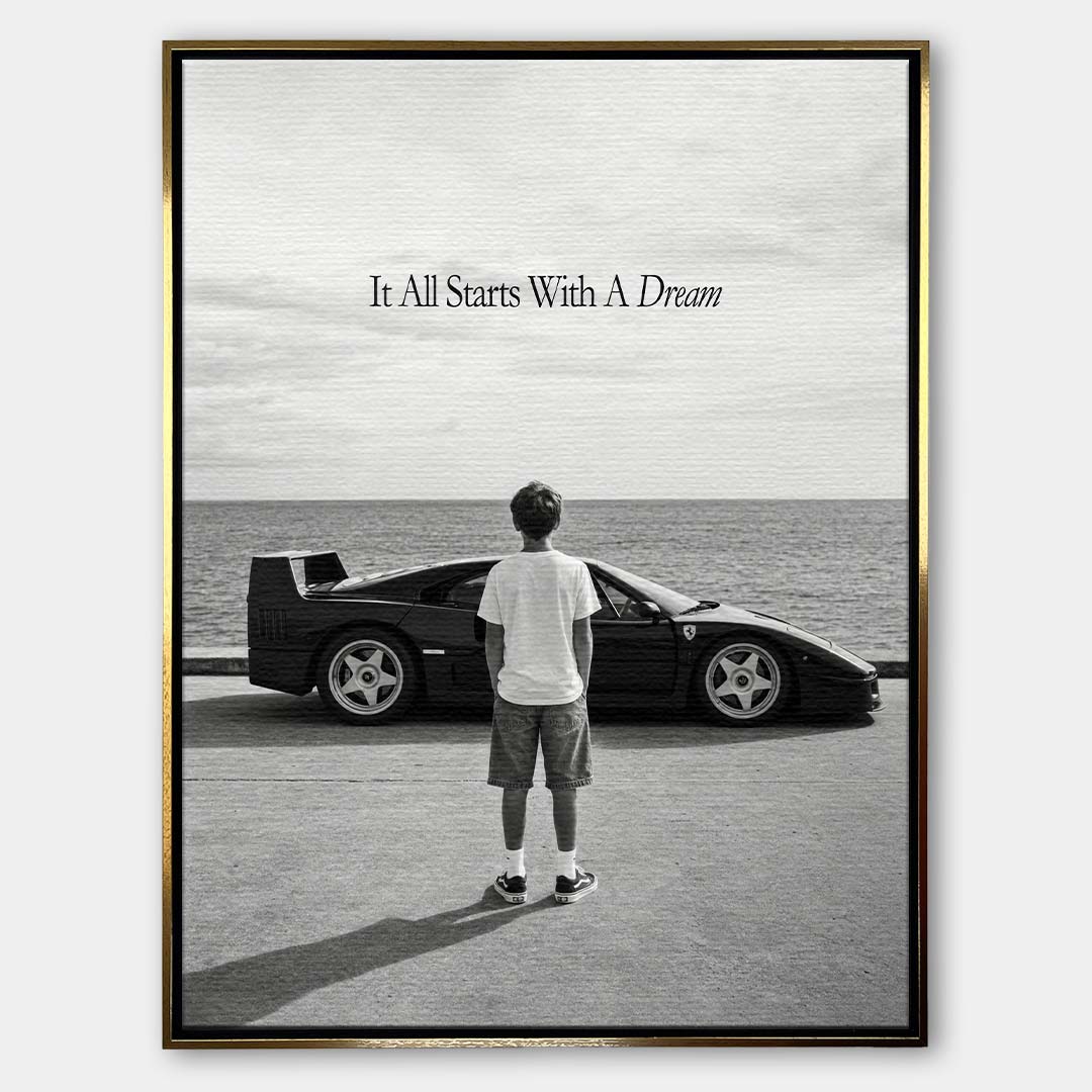 Czarno-biały obraz na płótnie przedstawiający chłopca patrzącego na sportowe auto i morze. Wydruk galeryjny z motywacyjnym napisem It All Starts With A Dream.