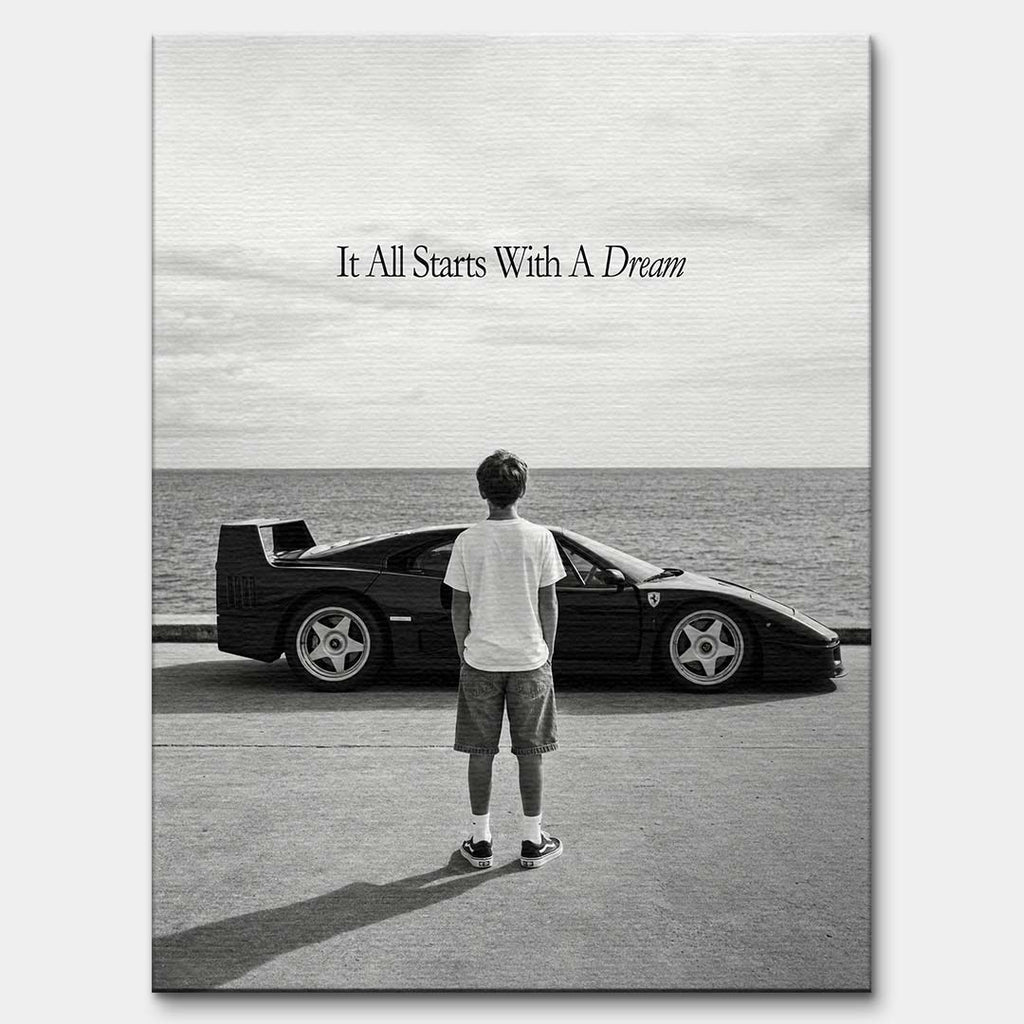 Czarno-biały obraz na płótnie przedstawiający chłopca patrzącego na sportowe auto i morze. Wydruk galeryjny z motywacyjnym napisem It All Starts With A Dream.