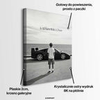 Czarno-biały obraz na płótnie przedstawiający chłopca patrzącego na sportowe auto i morze. Wydruk galeryjny z motywacyjnym napisem It All Starts With A Dream.