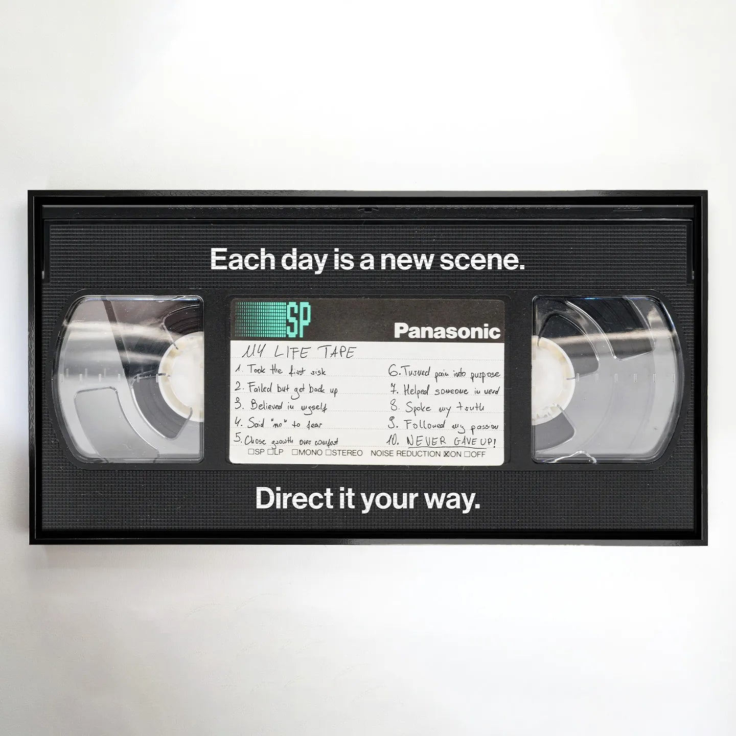 Obraz na płótnie "My Life Tape" przedstawiający kasetę VHS z inspirującymi hasłami o życiu, takimi jak "Never gave up" i "Each day is a new scene" – nowoczesna dekoracja ścienna w stylu retro z motywem motywacyjnym