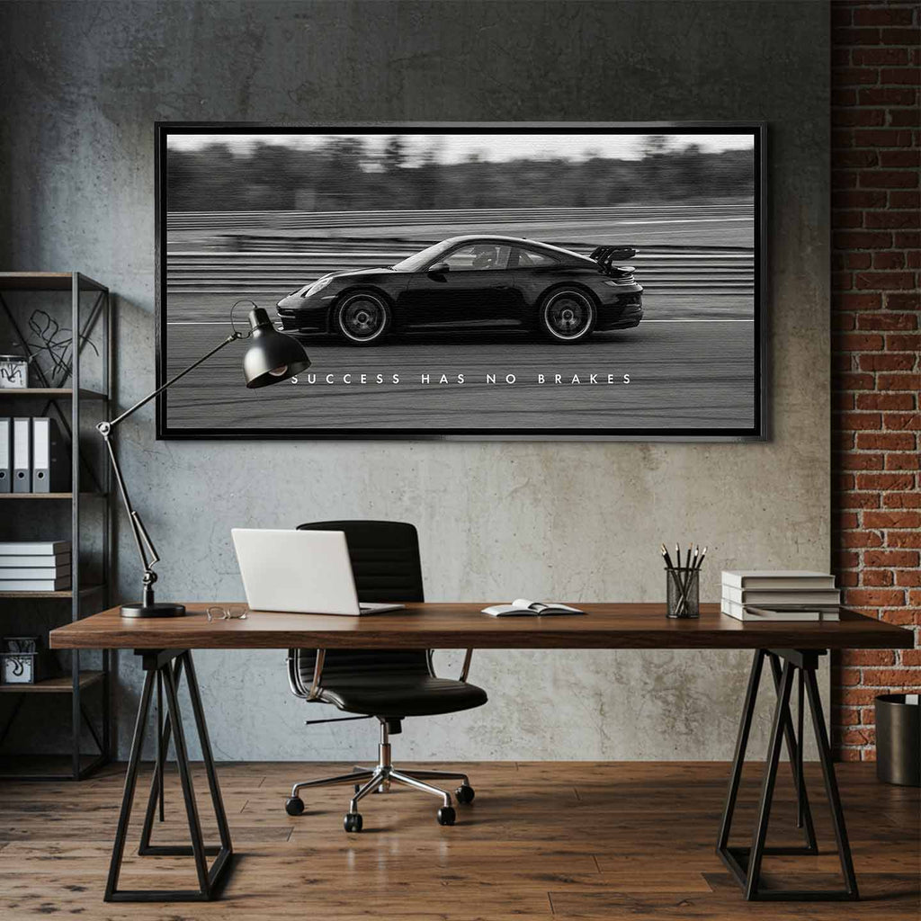 Czarno-biały obraz na płótnie przedstawiający Porsche 911 w szybkim ruchu na torze z napisem Success Has No Brakes. Motywacyjna sztuka ścienna do biura.