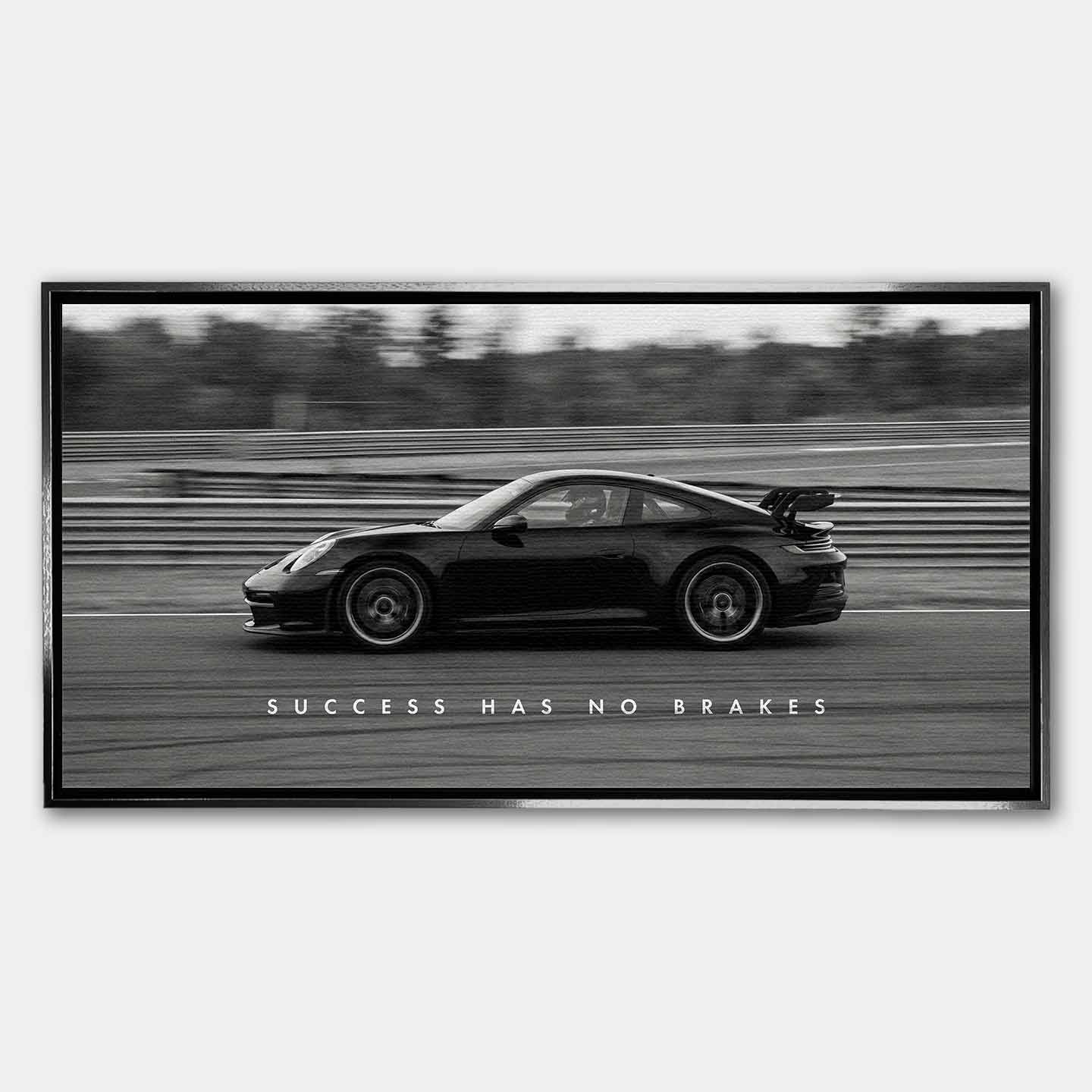 Czarno-biały obraz na płótnie przedstawiający Porsche 911 w szybkim ruchu na torze z napisem Success Has No Brakes. Motywacyjna sztuka ścienna do biura.