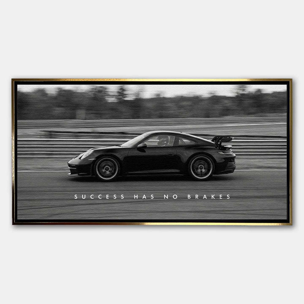 Czarno-biały obraz na płótnie przedstawiający Porsche 911 w szybkim ruchu na torze z napisem Success Has No Brakes. Motywacyjna sztuka ścienna do biura.