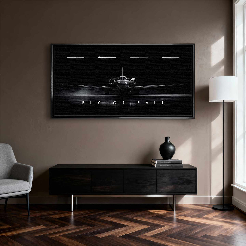 Obraz motywacyjny na płótnie Fly or Fall przedstawiający prywatny odrzutowiec w ciemnym hangarze z napisem „Fly or Fall”, symbolizujący luksus, odwagę i determinację.