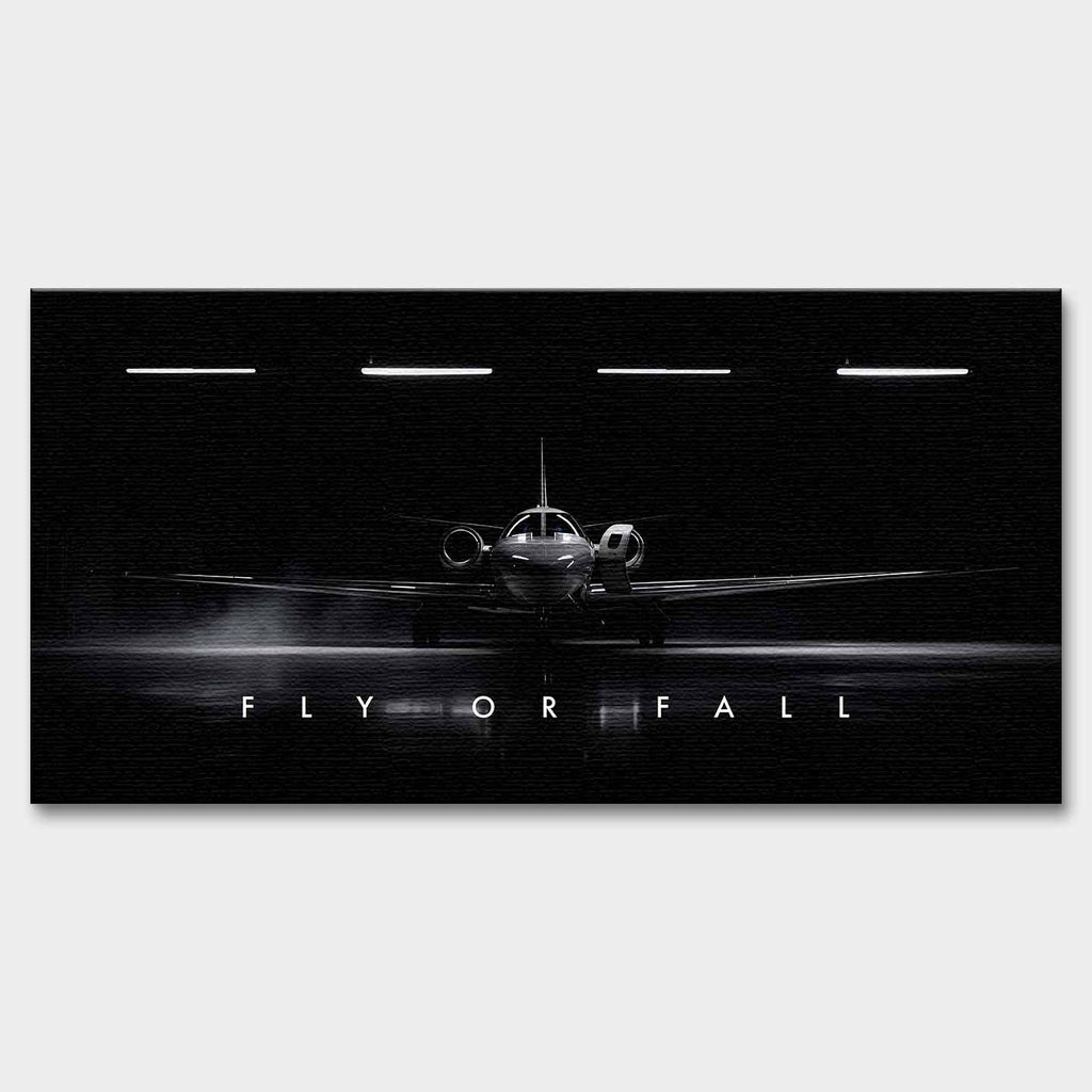 Obraz motywacyjny na płótnie Fly or Fall przedstawiający prywatny odrzutowiec w ciemnym hangarze z napisem „Fly or Fall”, symbolizujący luksus, odwagę i determinację.
